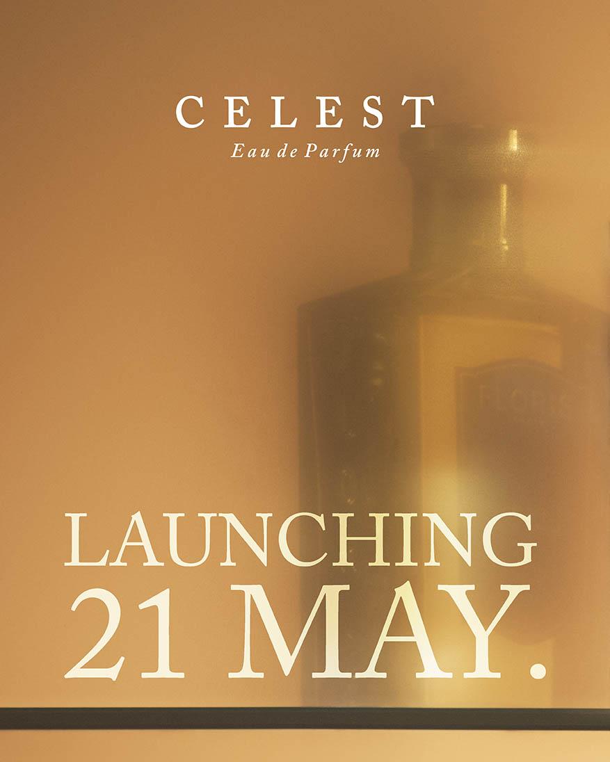 A blurred perfume bottle with text reading "CELEST Eau de Parfum. Launching 21 May." against a soft beige background.