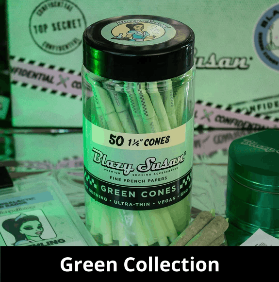 A clear plastic jar filled with 50 green-tinted 'Blazy Susan Green Cones' stands in the center. The label is light green with black text stating 'Fine French Papers' and 'Ultra-Thin'. The background is dimly lit with green light, showing a green herb grinder and 'Top Secret' themed packaging. A black banner at the bottom reads 'Green Collection'.