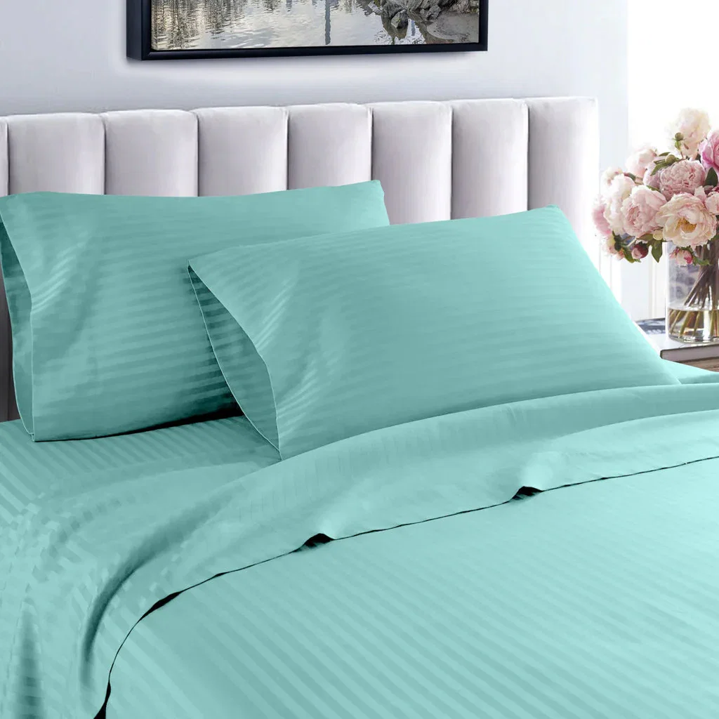 Mint green striped bedding set with pillows on white upholstered headboard, styled bedroom with flowers.