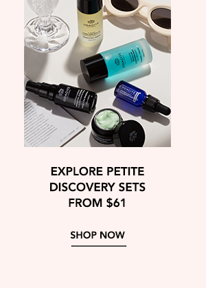 Assorted Odacité Petite skincare products laid out on a flat surface alongside sunglasses and a wine glass