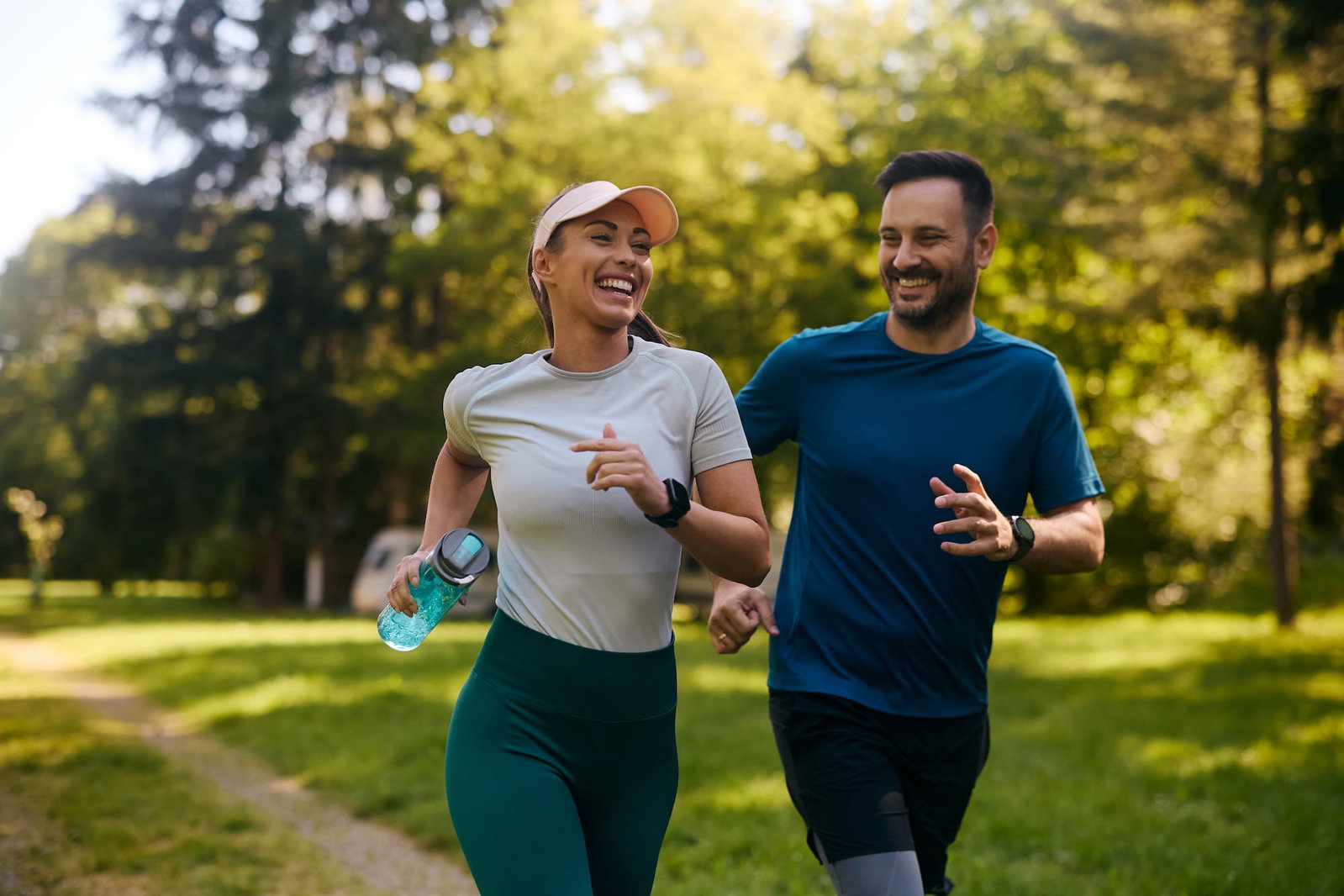 Smiling couple running outside on a trail on a sunny day