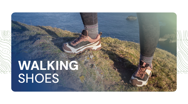 WALKING SHOES. A woman stands on a cliff wearing Salomon Women's X Ultra 5 GORE-TEX Hiking Shoes in Purple. 