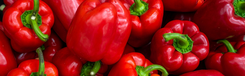 A pile of ripe red bell peppers. 
