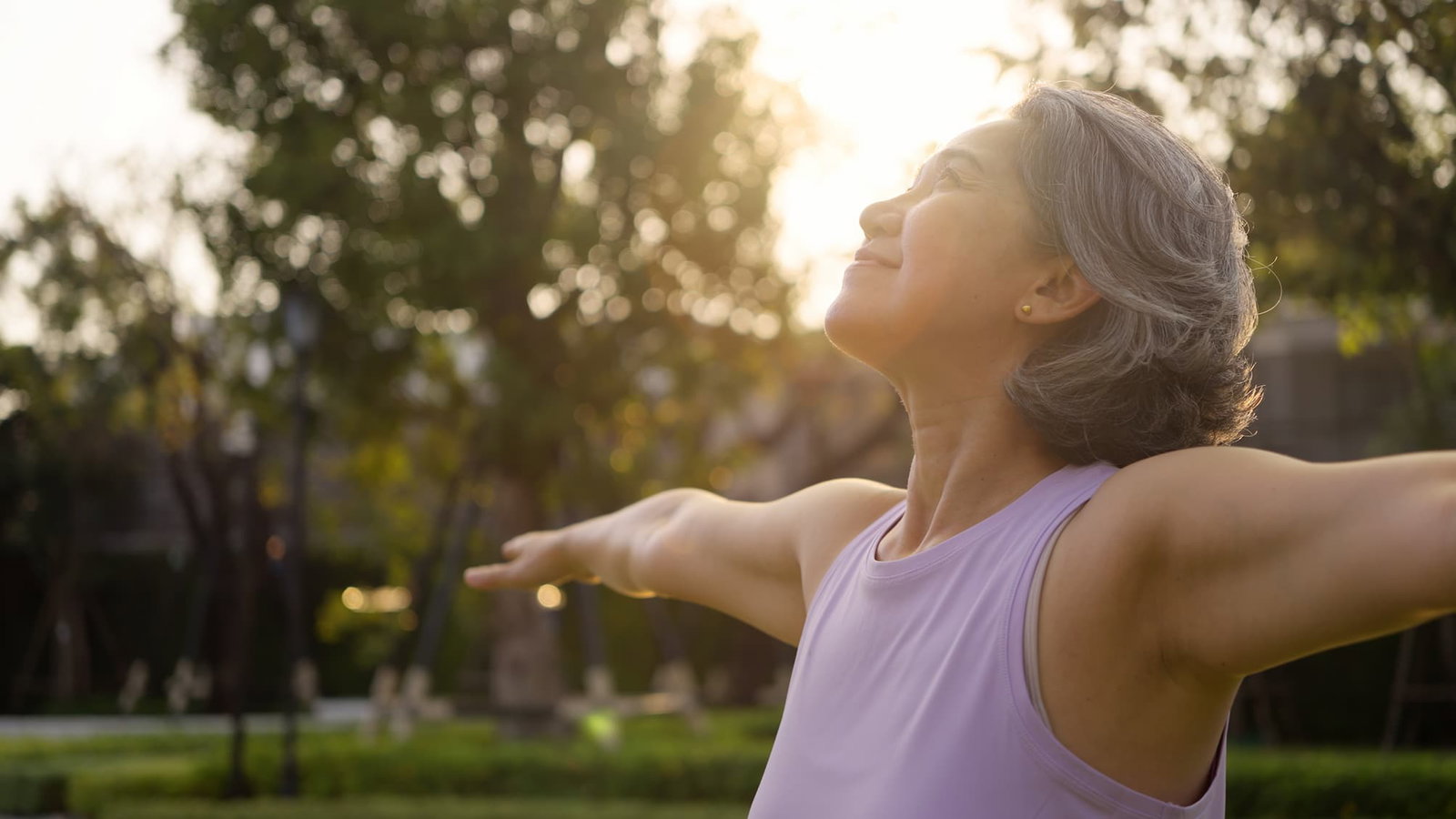 Woman smiling and making a bicep while holding a yoga mat. Read our blog on bone health.
