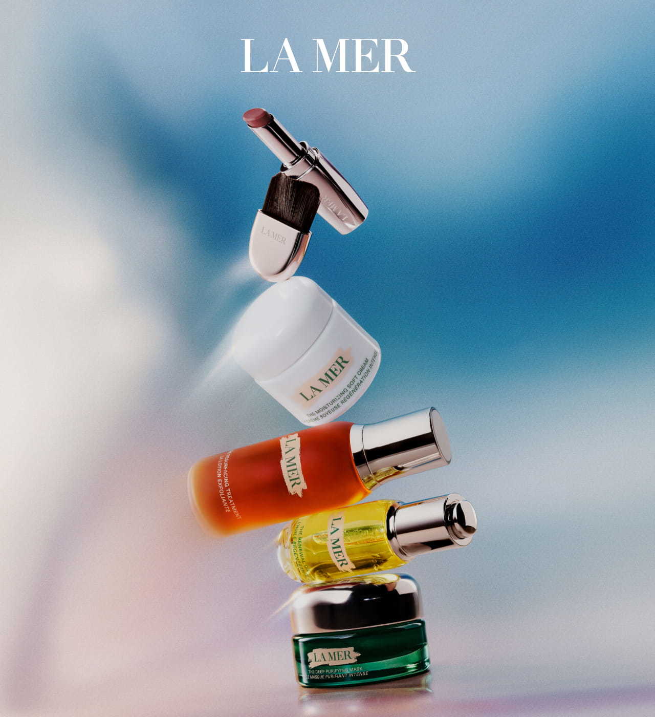 A collection of La Mer beauty products arranged vertically against a smooth gradient blue and white background.