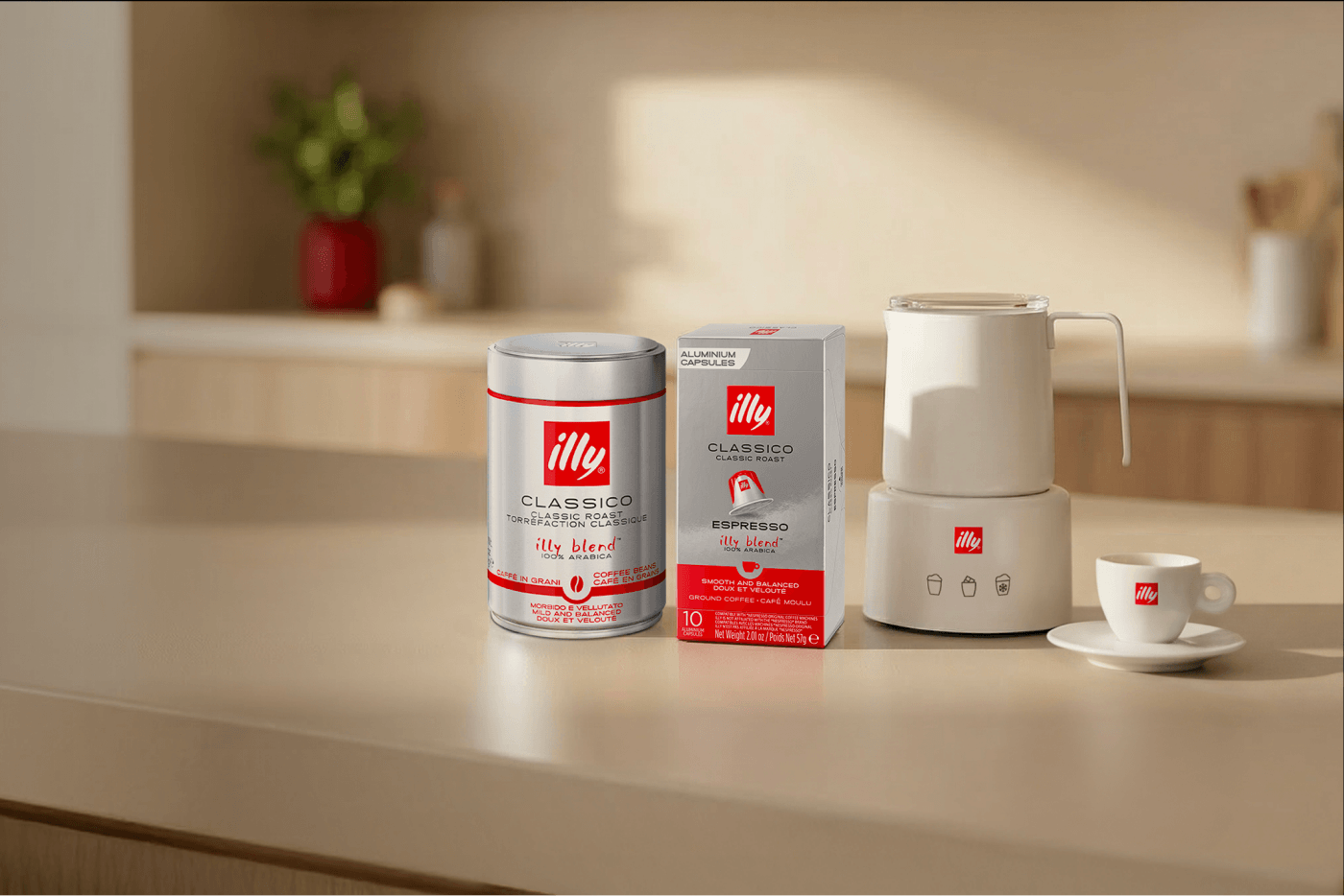 Illy coffee products and milk frother displayed on a kitchen counter beside an espresso cup