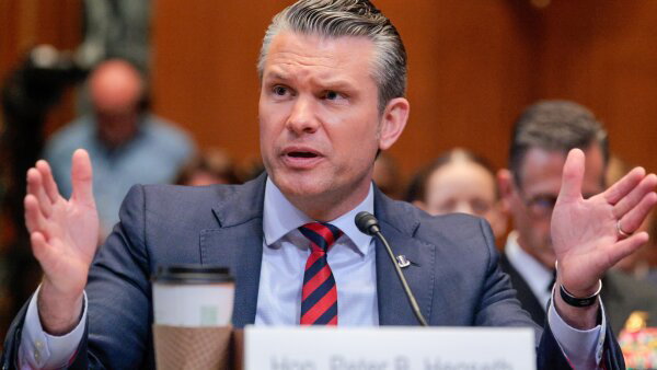 Defense Secretary Pete Hegseth testifies before the Senate Appropriations Committee. He is wearing a dark gray suit with a black-and-red tie.