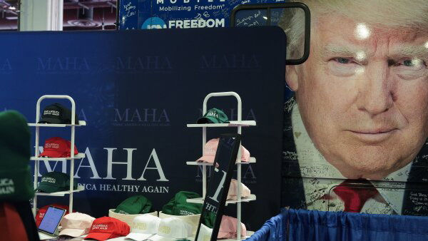 "Make America Healthy Again" merchandise is sold in front of a bus with President Trump's image.