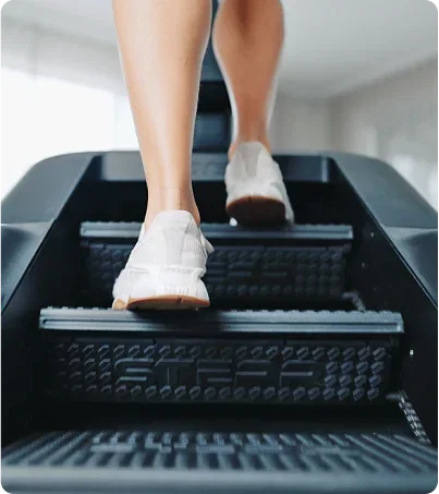 Woman in white tennis shoes climbing the STEPR PRO Plus