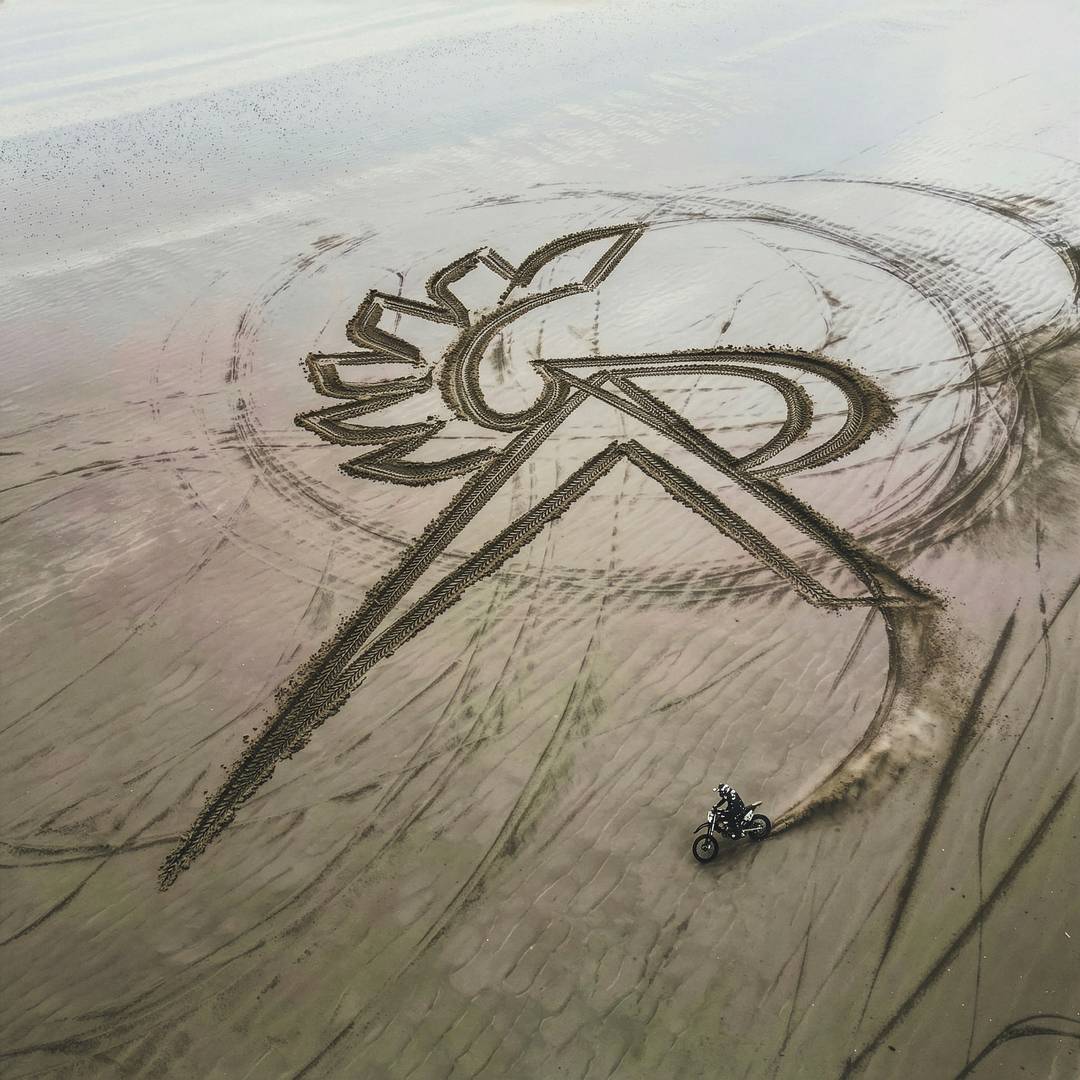 Represent x Belstaff logo in the sand
