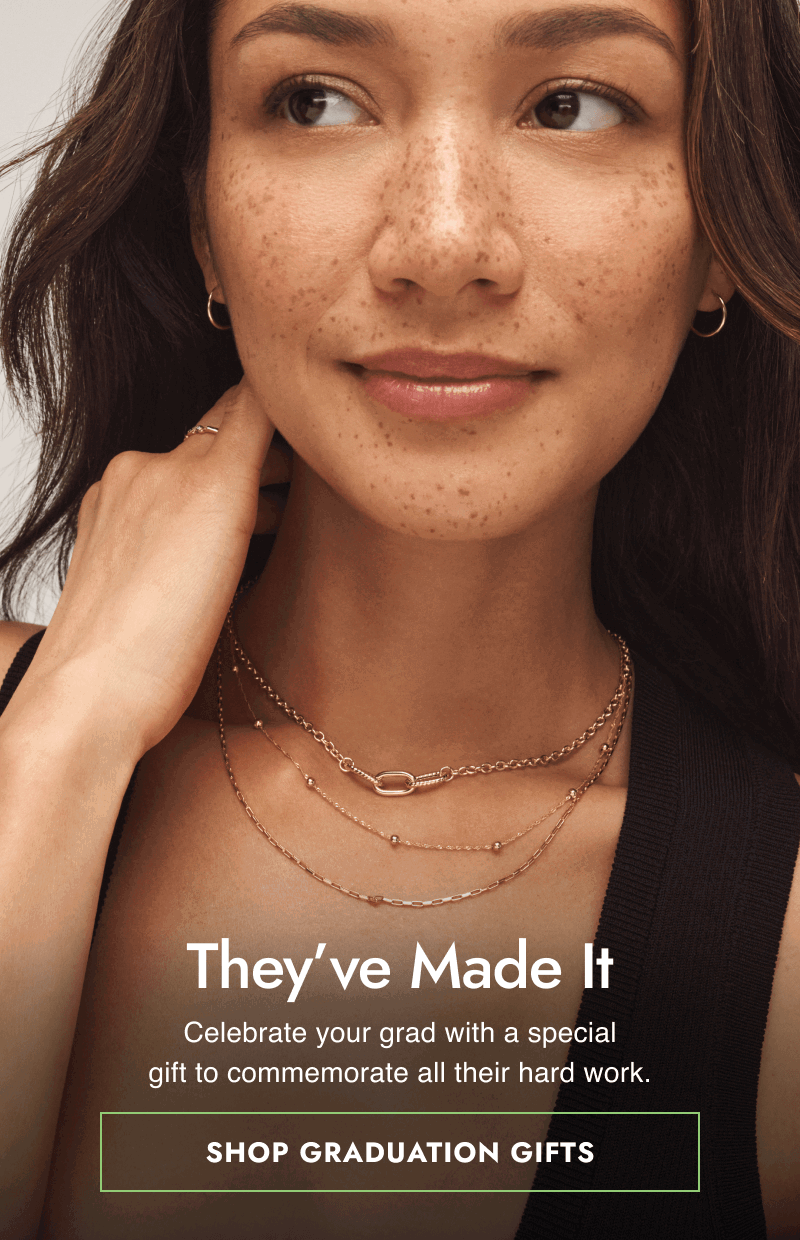 Female model wearing yellow gold hoops, ring and layered chain necklaces. They’ve made it. Click shop graduation gifts.