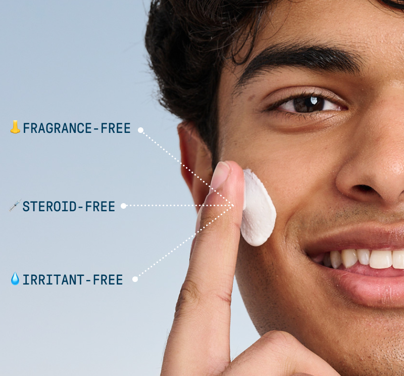 Close-up portrait of a smiling person applying white cream to their cheek with one finger against a soft blue background. Text callouts point to the cream and read “Fragrance-Free,” “Steroid-Free,” and “Irritant-Free.”