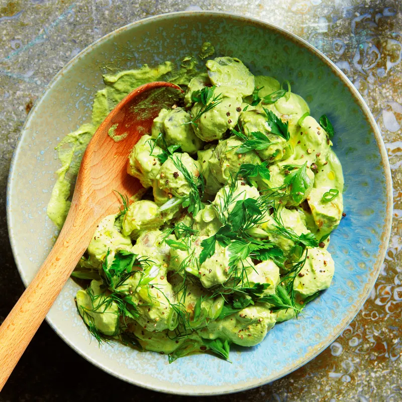 Pee-wee potatoes toss in a green-goddess dressing and topped with dill, parsley, and scallions.