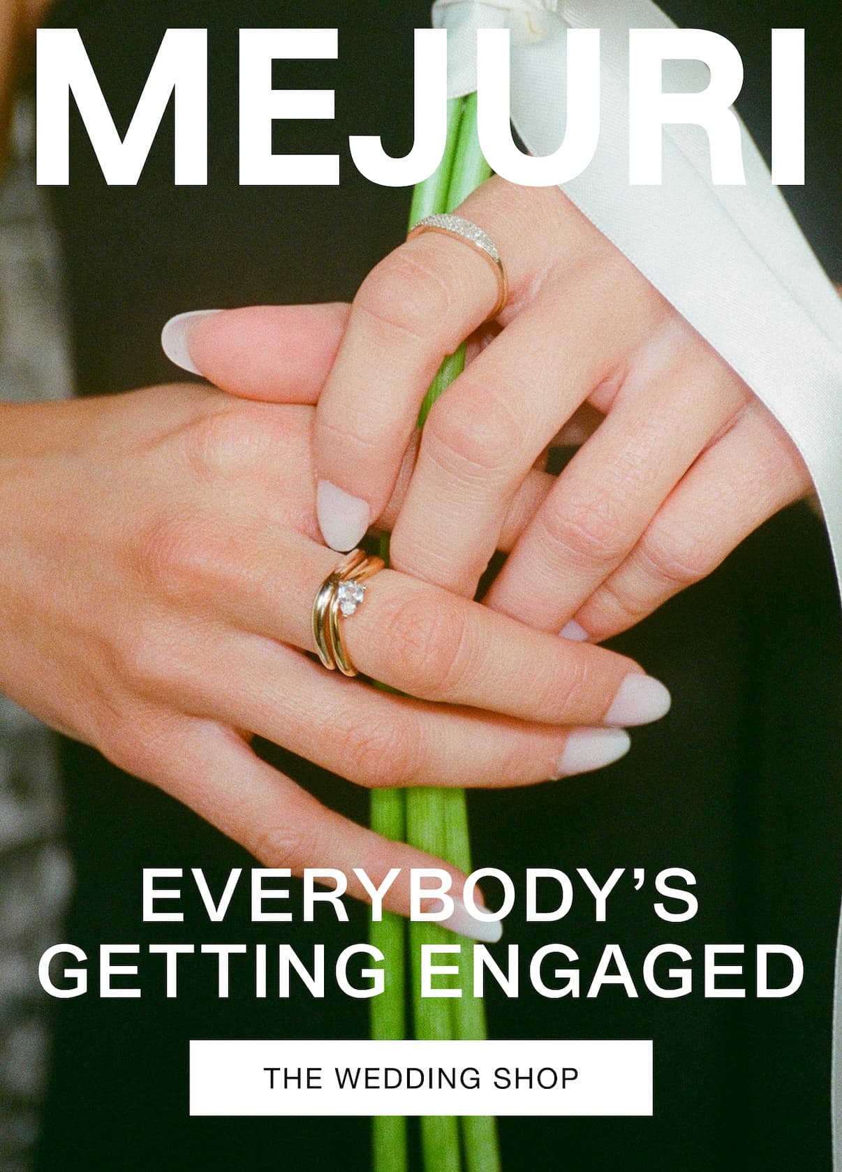 Two hands wearing diamond and gold rings holding a bouquet. Text reads: MEJURI. EVERYBODY'S GETTING ENGAGED. The Wedding Shop.