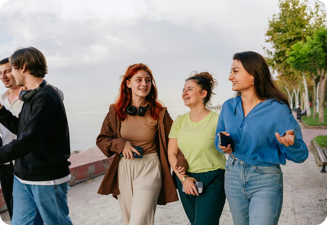 A group of teens is shown walking along a beach