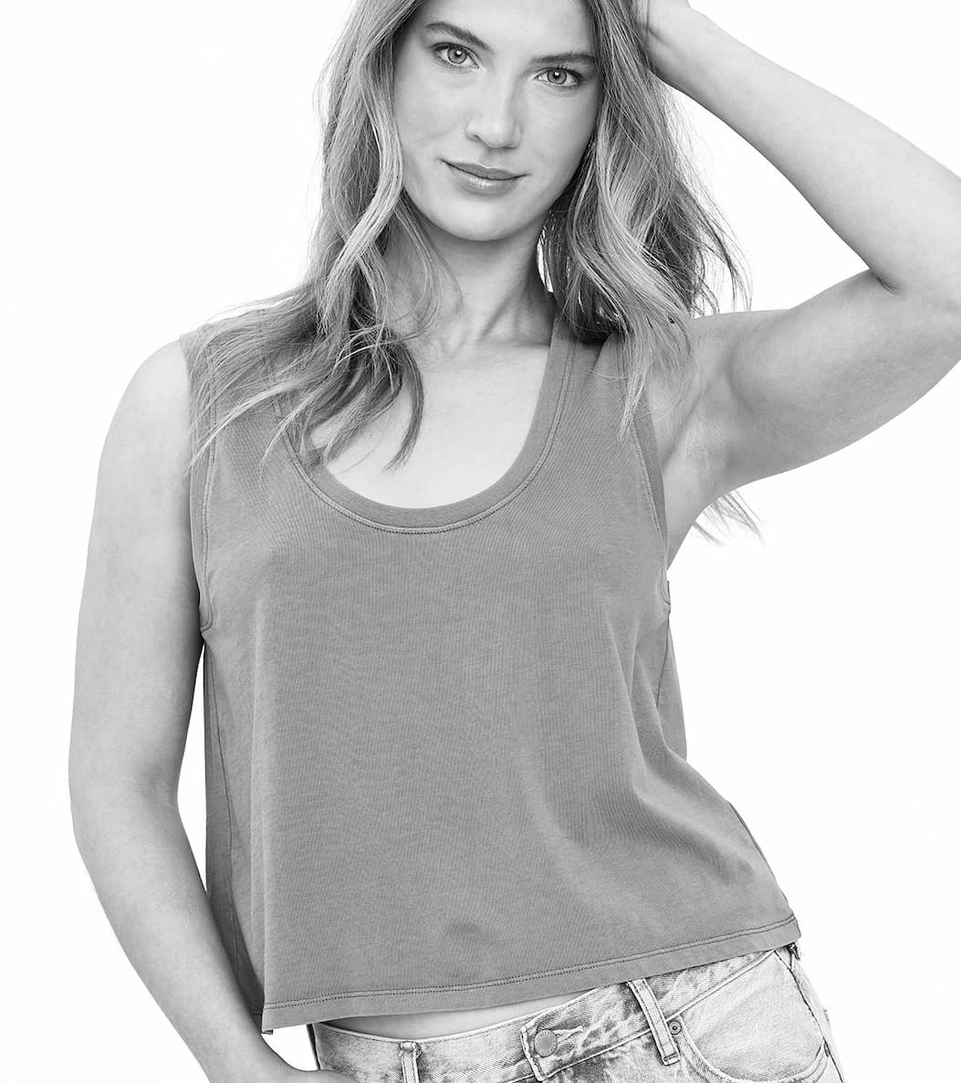 Model wearing a relaxed-fit sleeveless tank top paired with light-wash jeans against a neutral background.