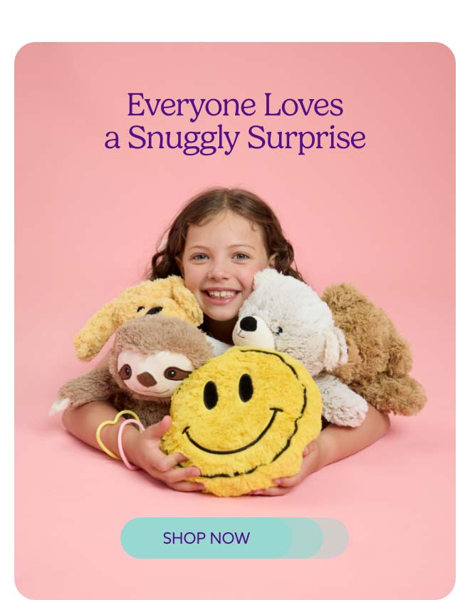 A little girl hugging a pile of Warmies. Shop Now.