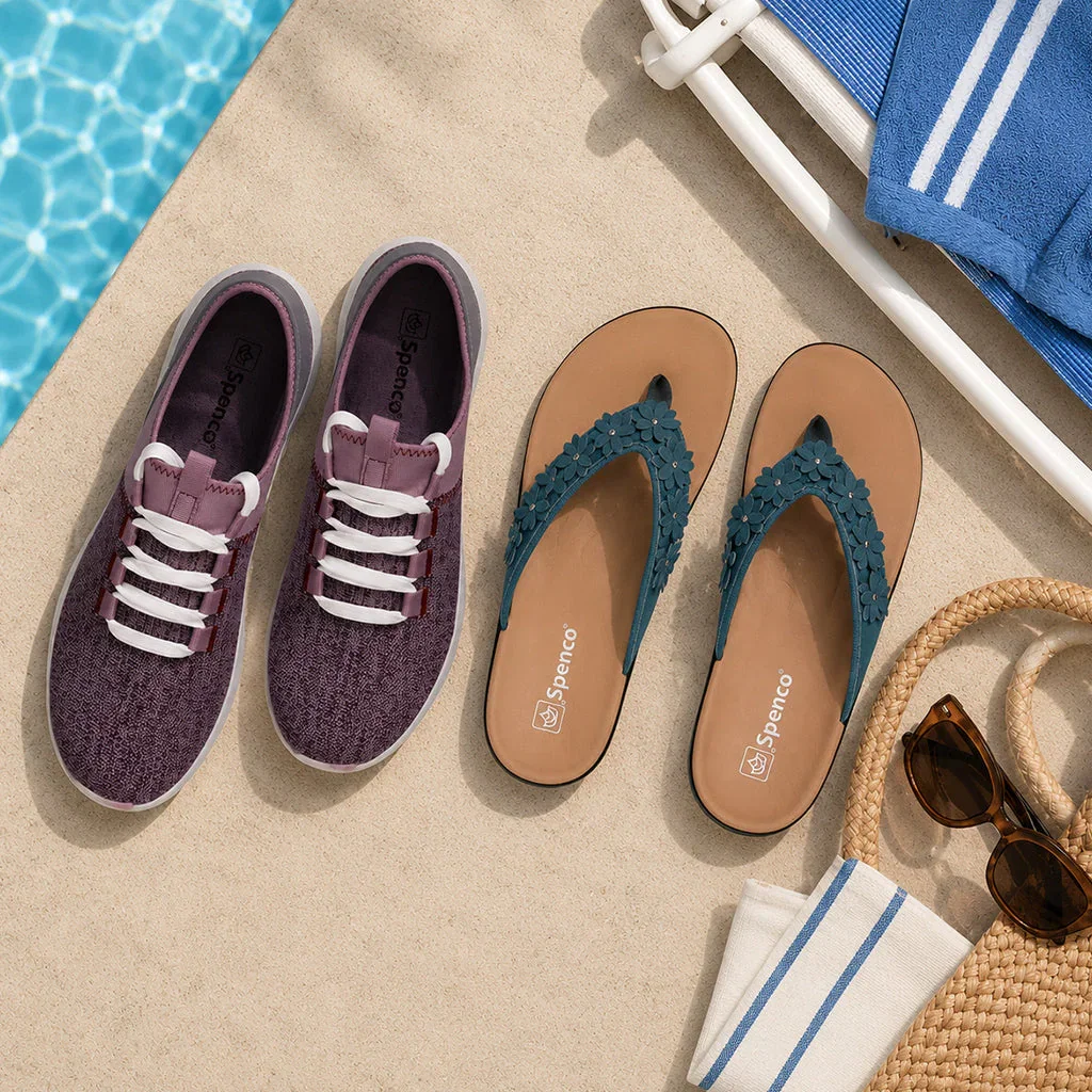 Spenco footwear collection displayed on sandy beach with pool, towels, sunglasses, and straw hat nearby.