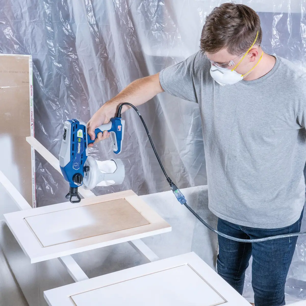 Man using the Graco Paint Sprayer to paint a cabinet door