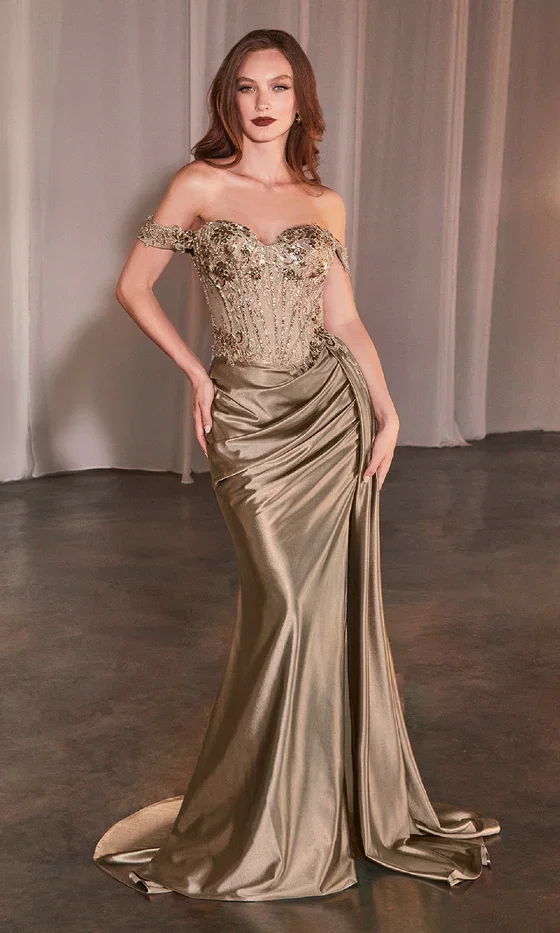 A woman in the Ladivine CD803 Off-the-Shoulder Long Prom Dress, featuring a metallic gold beaded corset-style bodice, draped satin skirt, and slight train, stands on a dark floor with sheer curtains behind her.