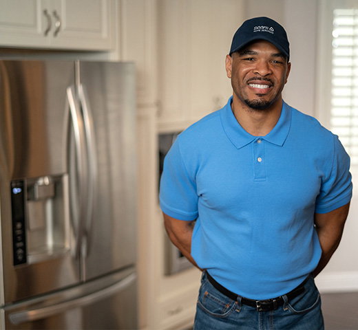 A smiling Sears Home Services technician in front of a fridge