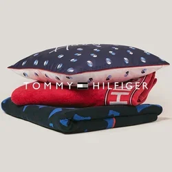 Stapeltje van drie gevouwen textielstukken: blauw patroonstof onderaan, rood stof met witte tekst in het midden, blauw kussen met witte en roze stippen bovenaan.