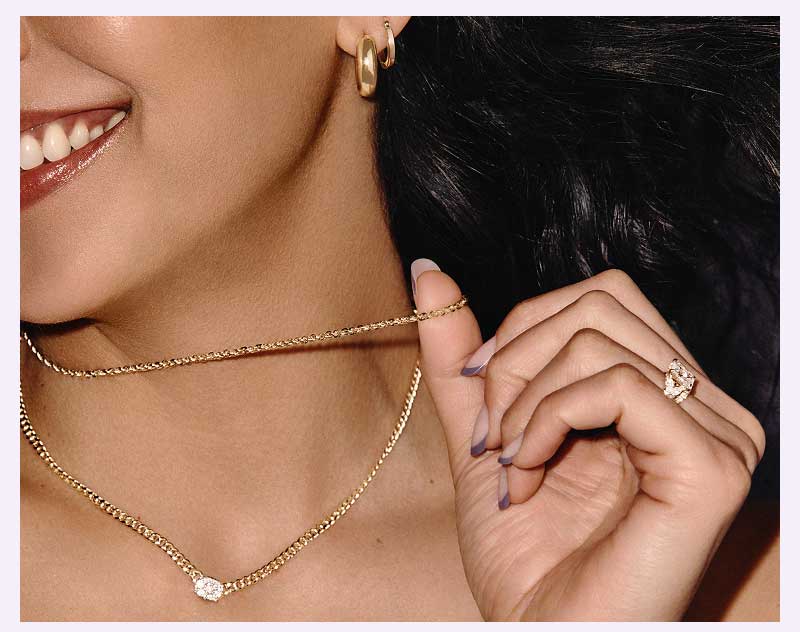 Model layered in gold-set jewelry, including chain with diamond pendant & gold hoops & huggies.
