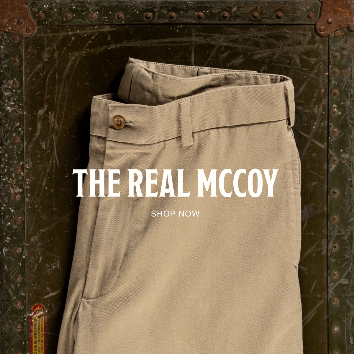 A pair of Bills Khakis Original Twill M1 Khakis on a vintage green chest. Text reads: The Real McCoy | Shop Now