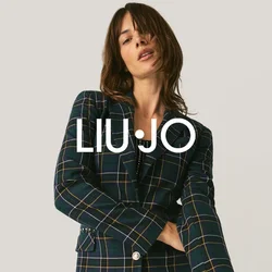 Vrouw poseert in een geruite blazer en zwarte paillettenbroek tegen een effen lichte achtergrond.
