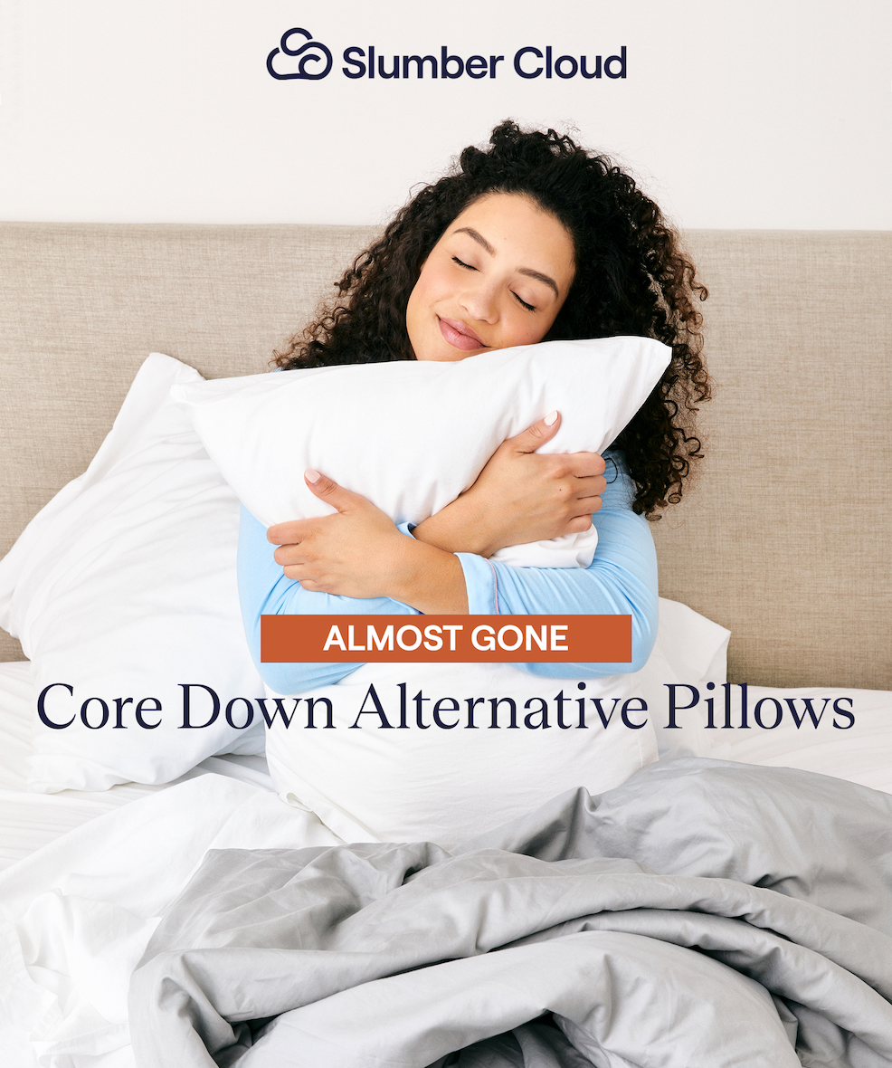 Woman sitting in bed hugging the Core Down Alternative Pillow