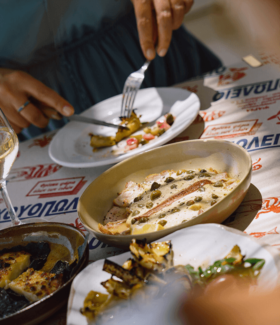 A close-up of shared Mediterranean-style dishes on a restaurant table.