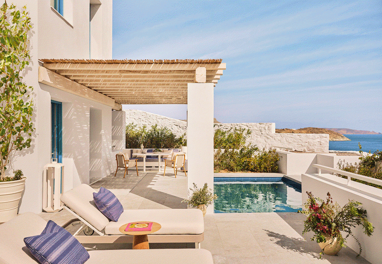 Hero GIF featuring 3 frames: 1) White stucco terrace with two cushioned loungers, a shaded pergola dining area, and a small private pool overlooking the ocean. 2) Covered outdoor lounge with wicker sofa seating, striped cushions, a small table with two glasses, and a vase of flowers facing a sea view. 3) Row of traditional white windmills along the waterfront at sunset with low white buildings and calm water in the foreground.” 