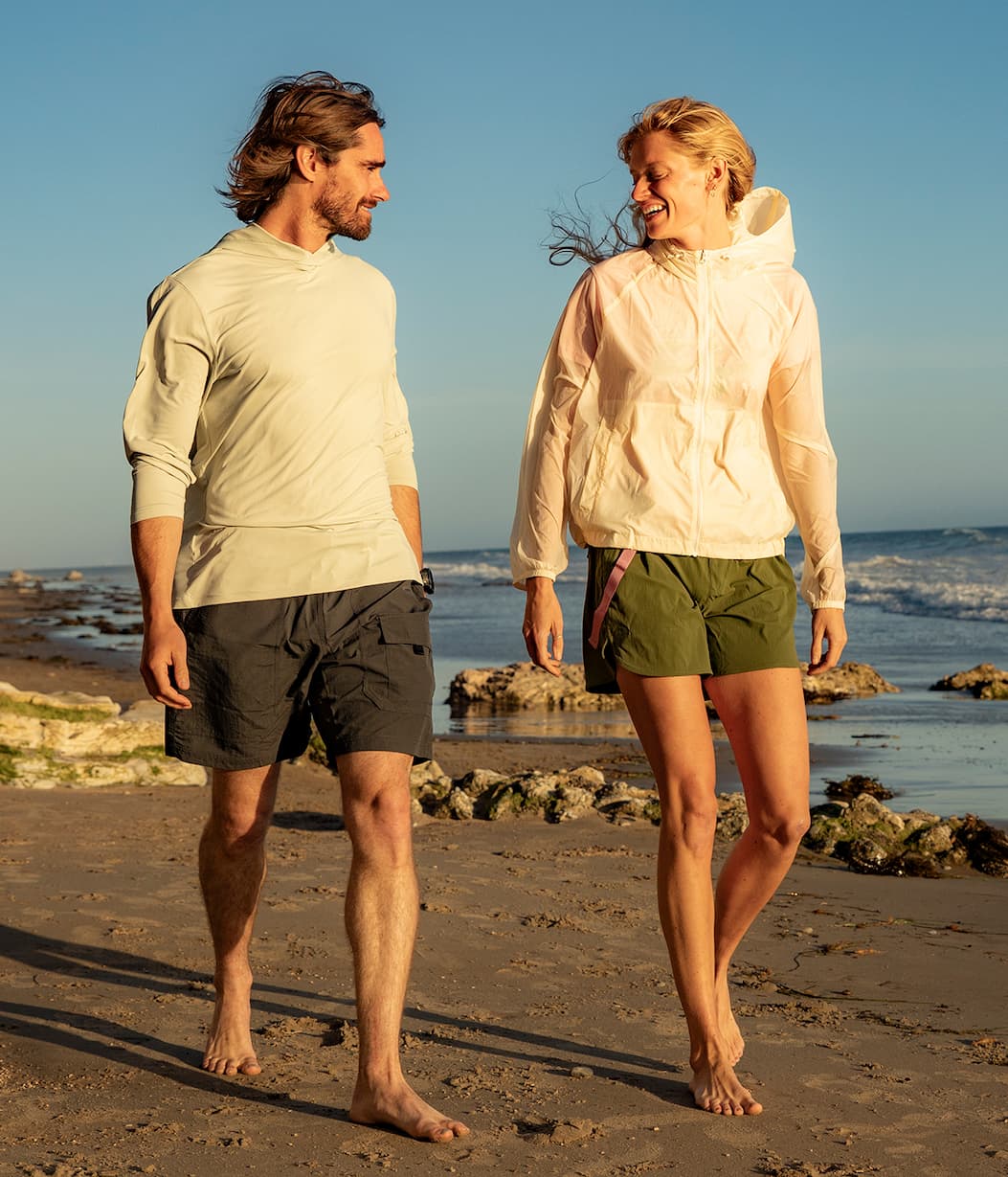 Man and woman walking on a beach in Eddie Bauer clothing. 