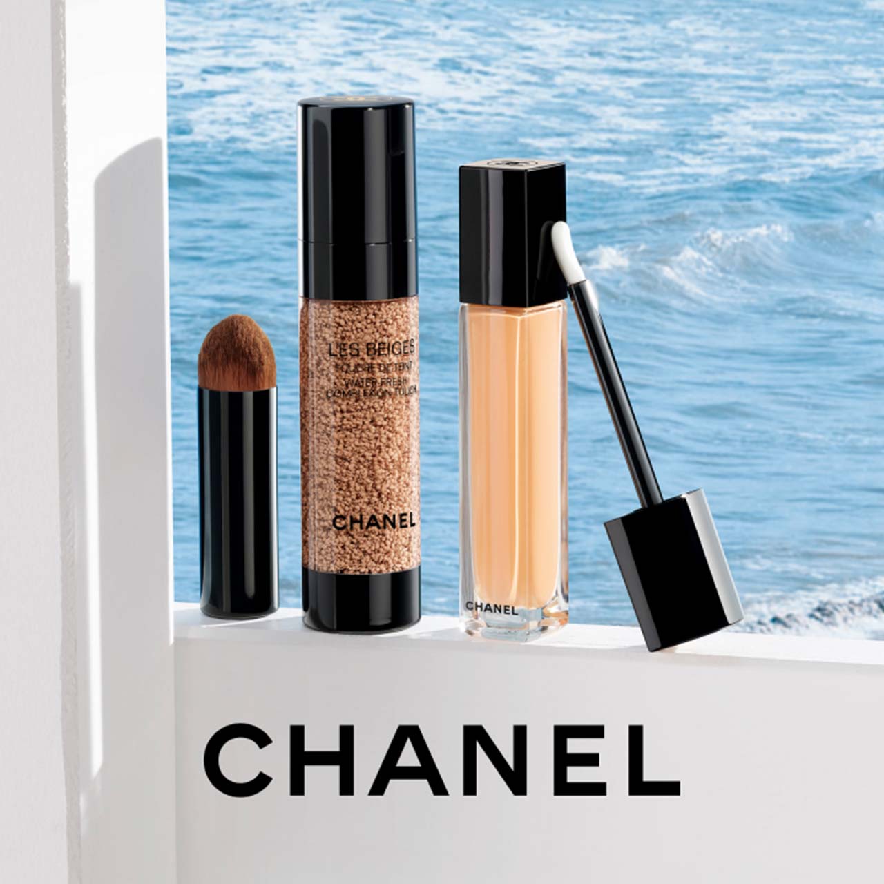 Chanel makeup products on a ledge with a sea view in the background.