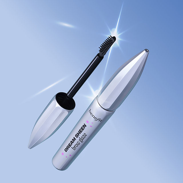 A silver Benefit mascara tube with a brush applicator on a light blue background.