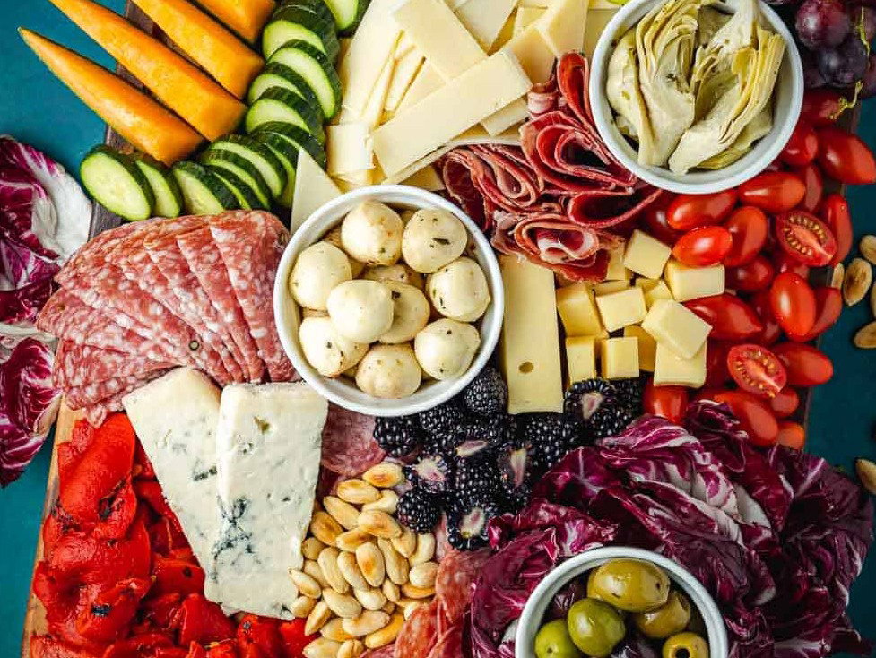 An antipasto platter showcasing different meats, cheeses, fruits, vegetables and nuts.