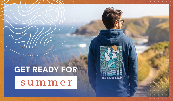GET READY FOR SUMMER. A man looks out across the coast, wearing Bleubird Men's Trailhead Hoodie in Navy.