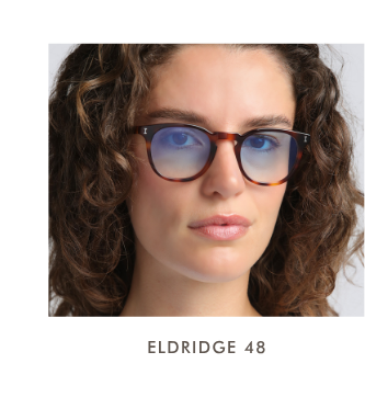 A headshot of a woman with curly brown hair wearing the Eldridge 48 (the small size) in a classic tortoise-shell frame with light-blue gradient lenses.
