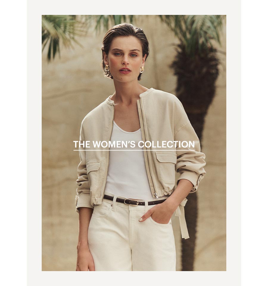 An image of a woman wearing a light cream colored safari inspired jacket paired with ecru colored denim jeans, white tank top and thin black leather belt. Shop The Women's Summer '26 Colletion.