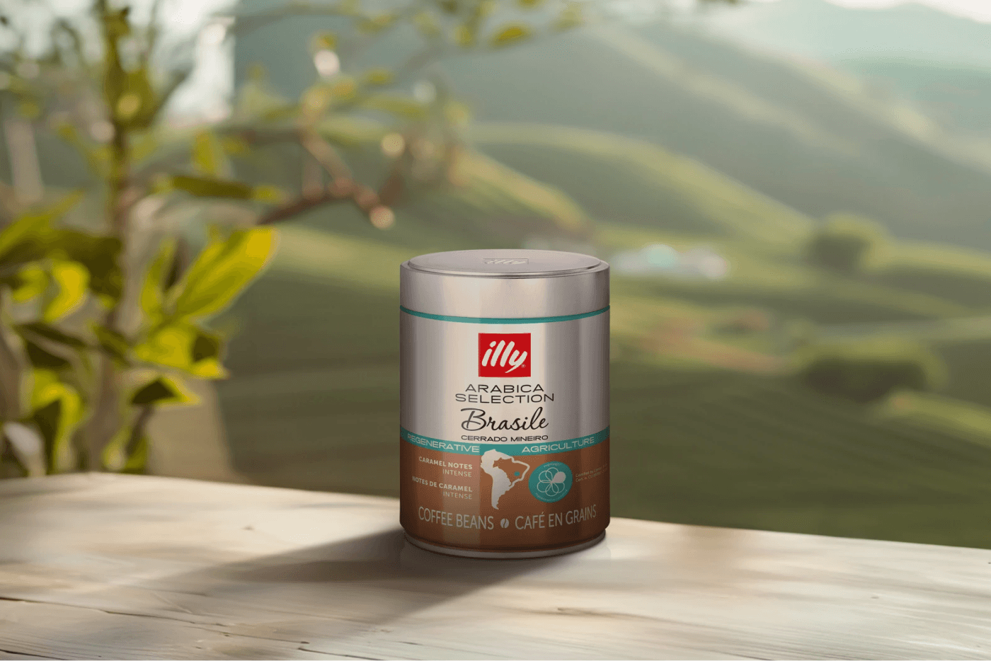Illy Arabica Selection coffee beans can displayed against a scenic hillside backdrop