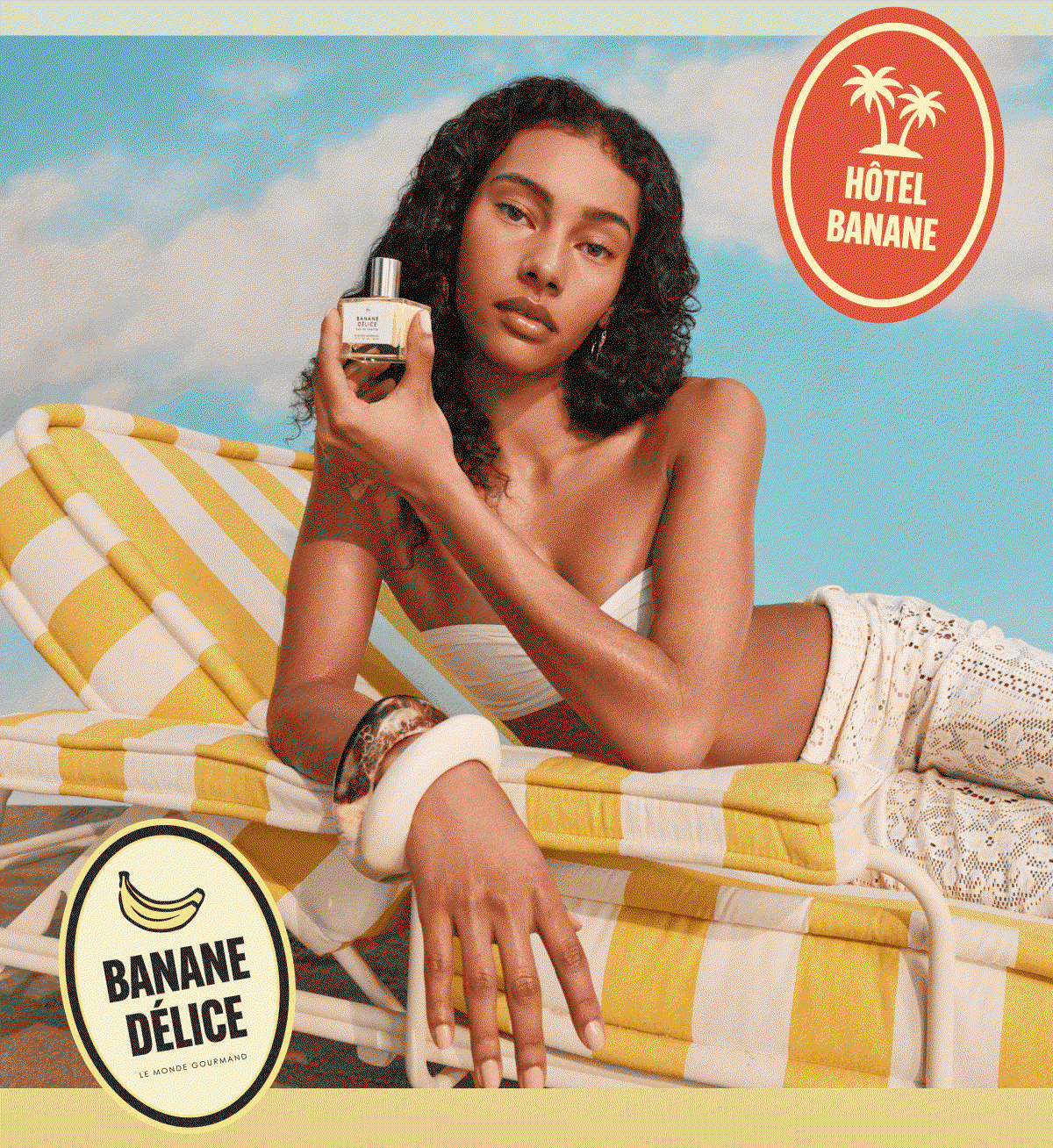 Model lounging on a striped beach chair holding a bottle of Banane Délice fragrance against a sunny blue sky backdrop.
