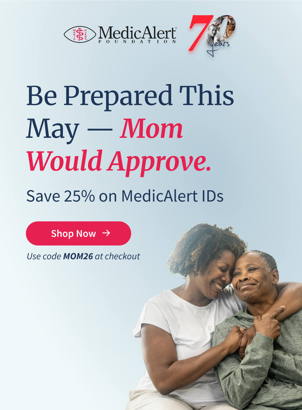 Promotional image for MedicAlert Foundation's 70th anniversary sale. The main text reads 'Be Prepared This May — Mom Would Approve. Save 25% on MedicAlert IDs'. There is a red button labeled 'Shop Now'. Below the button, text specifies, 'Use code MOM26 at checkout'. The image shows a portrait of two smiling African American women, a younger woman embracing an older woman.