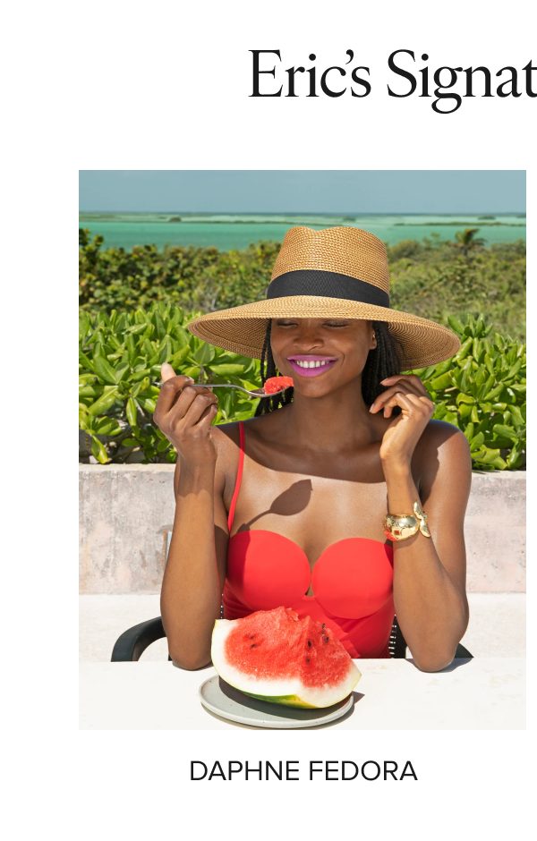 Woman in a red swimsuit and straw hat enjoying watermelon by the beach.