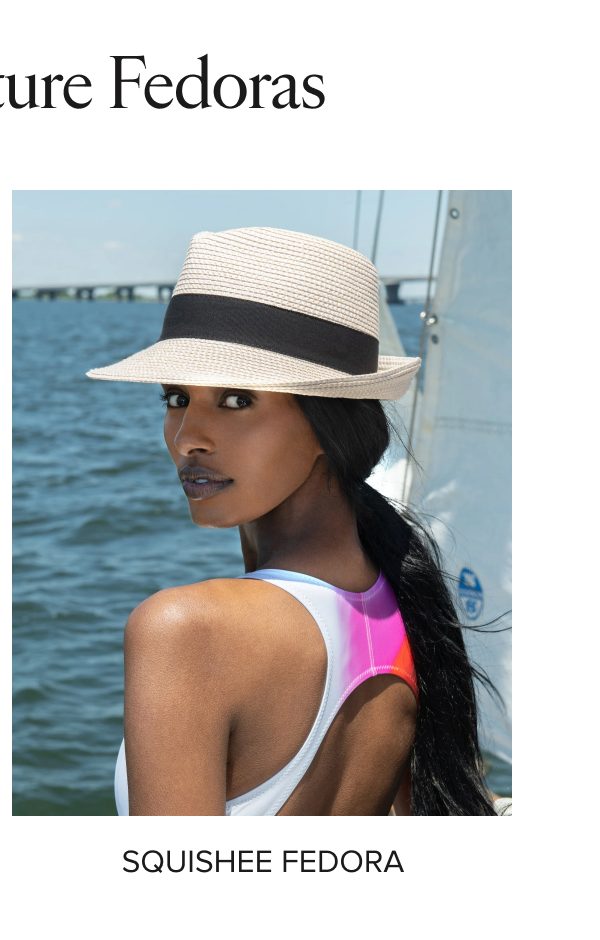A woman wearing a straw fedora hat by the water.