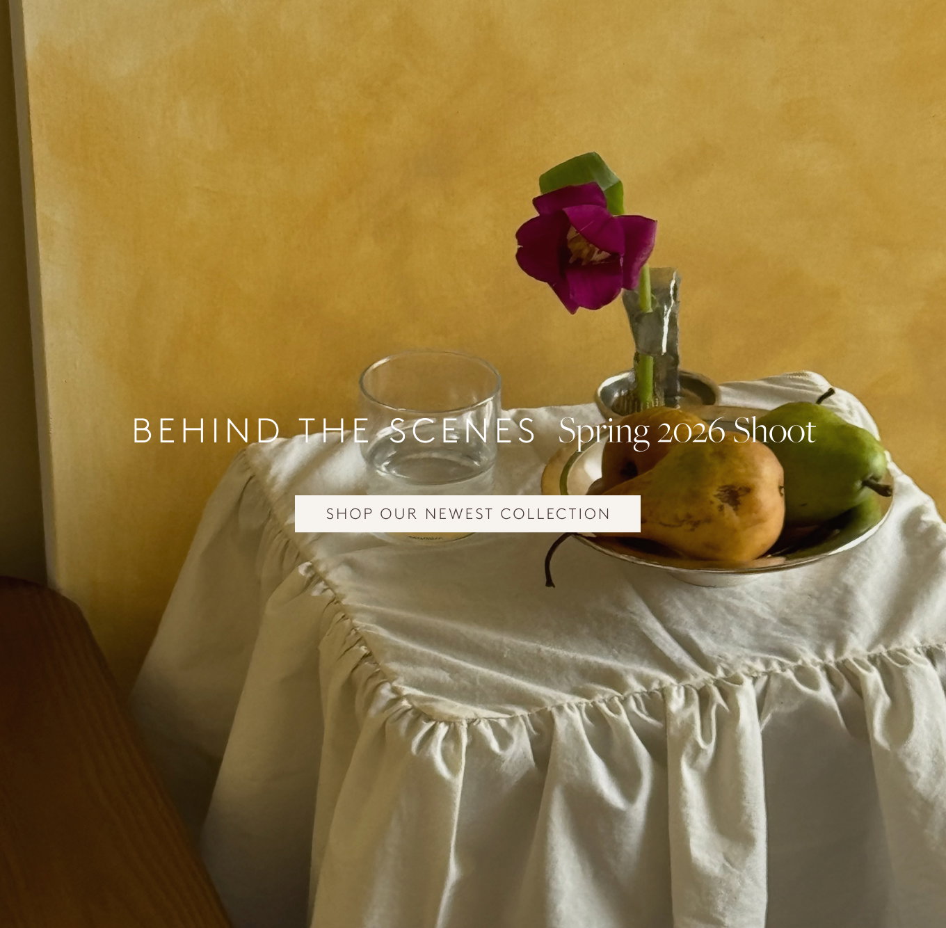 Side table with pears in a silver bowl, pink flower in a silver vase, and a glass of water