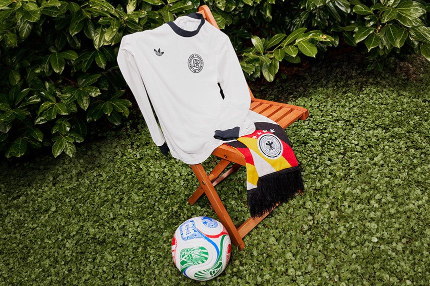 Fußballtrikot, Schal und Ball auf Stuhl im Garten.