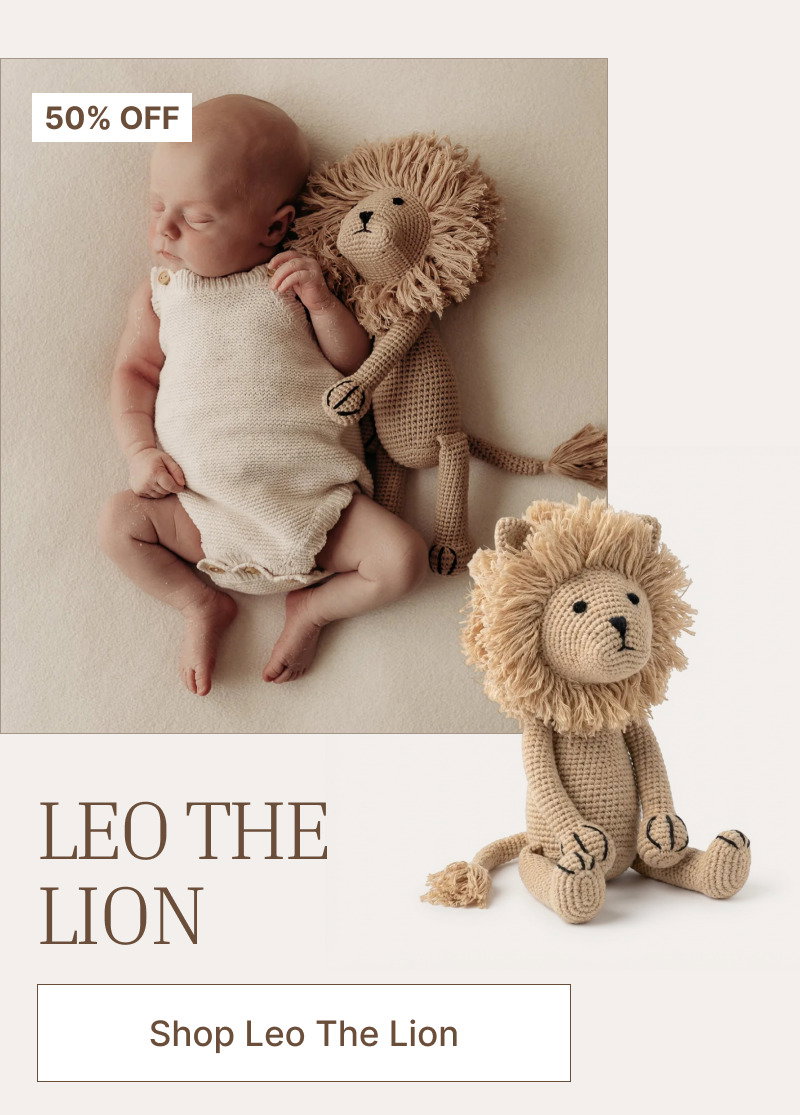 Sleeping baby wrapped in a light blanket beside a plush lion toy, with a second lion toy shown in front.