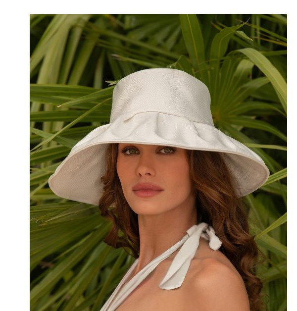 A woman in a colorful dress poses with a straw hat near flowers. Another woman wears a white hat in a tropical setting.