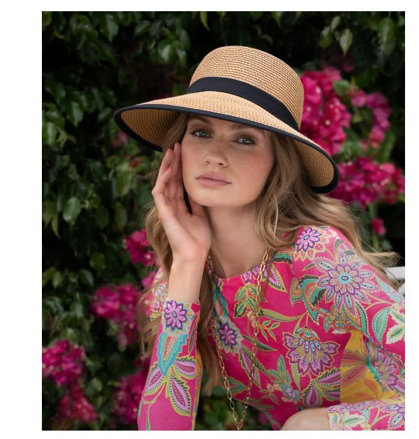 A woman in a colorful dress poses with a straw hat near flowers. Another woman wears a white hat in a tropical setting.