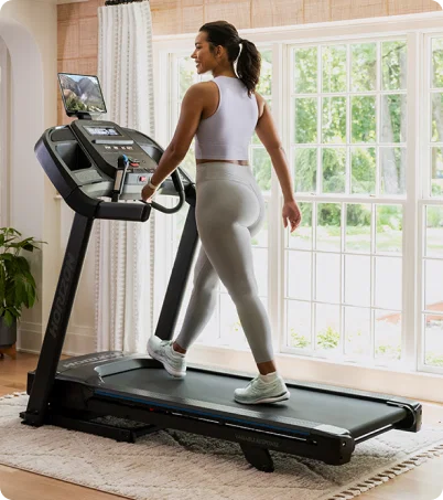 Woman in white walking on treadmill in home